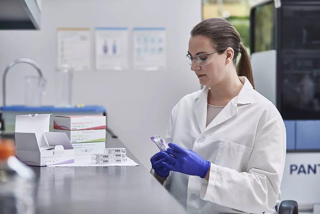 Lab technician with multiple assay boxes in lab background